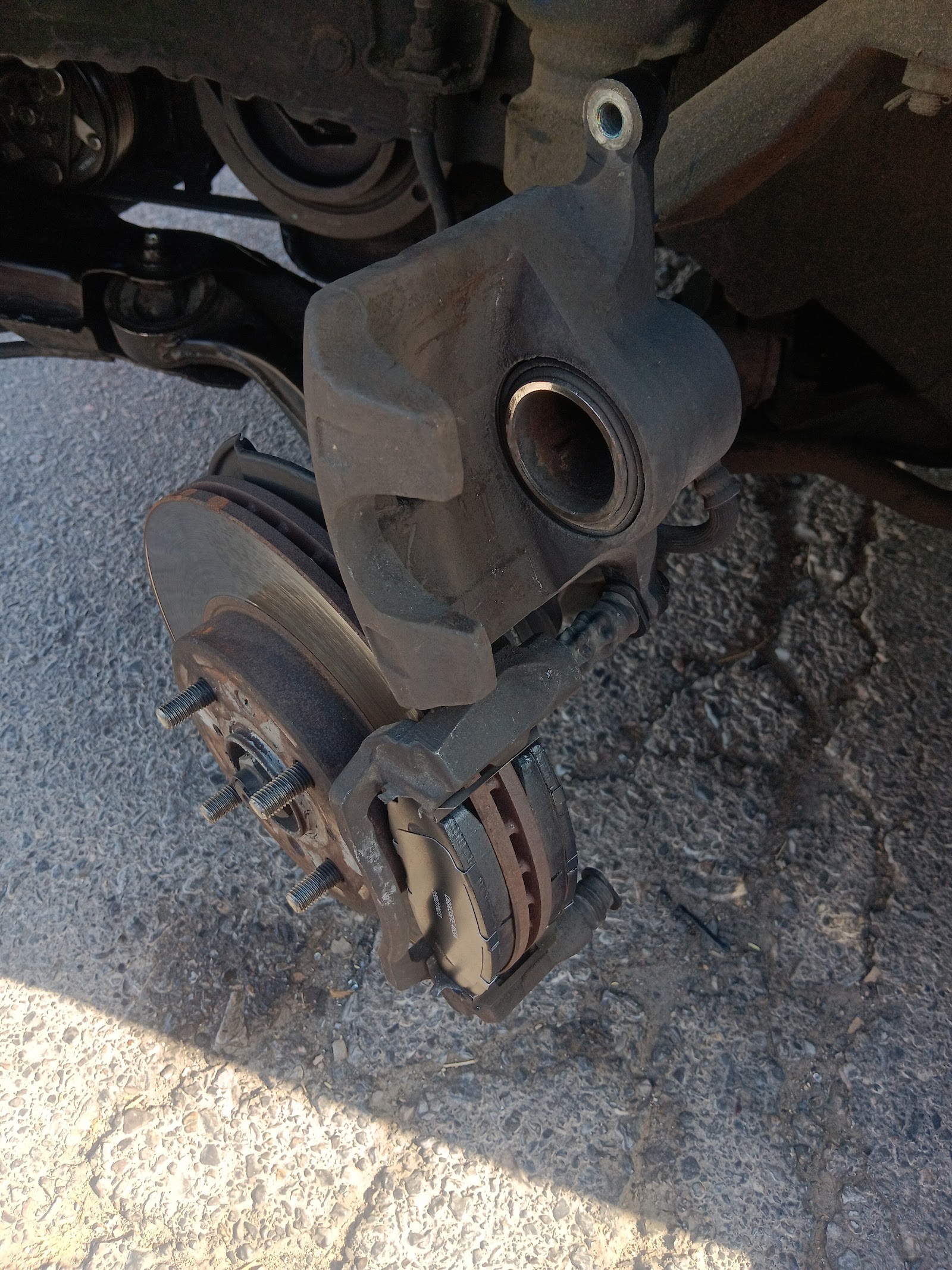Front brake caliper, rotor and pads exposed on a vehicle hub